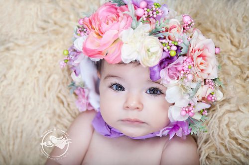 צילומי תינוקות מרהיבים. תינוקת עם כובע פרחים בתקריב